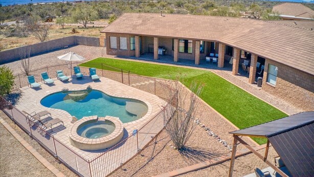 A house with a swimming pool, a patio with lounge chairs, and a well-maintained lawn.