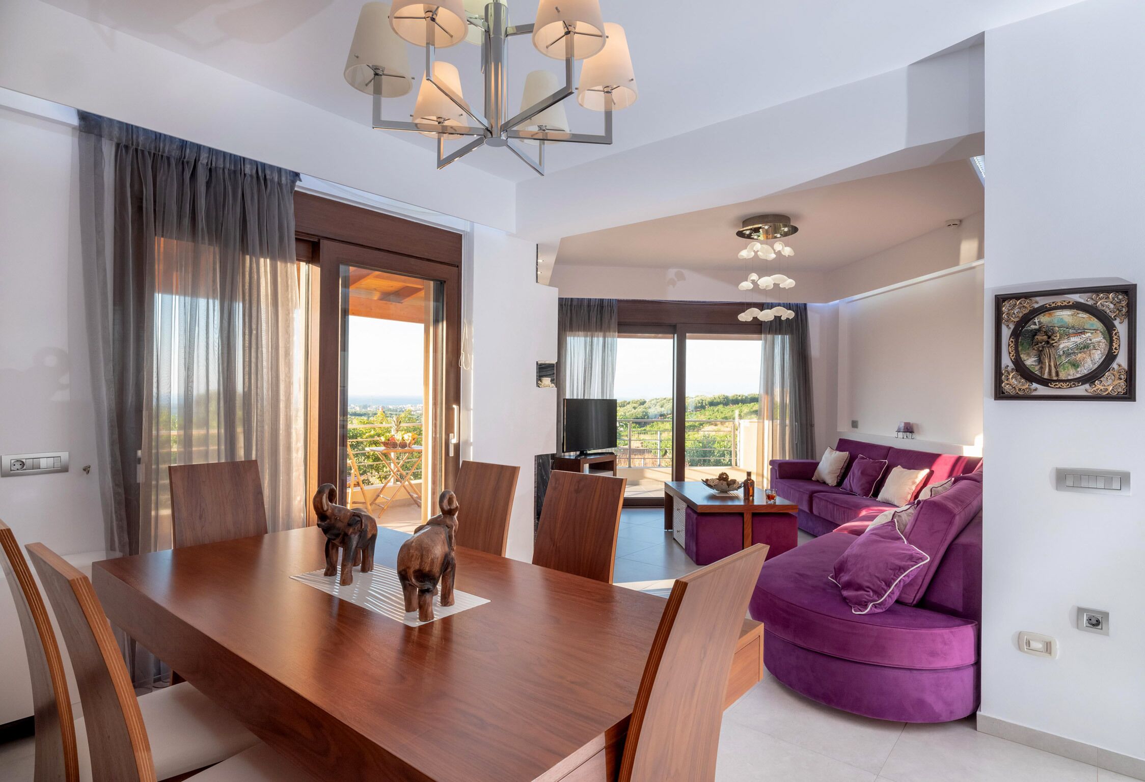 Ein modernes Wohnzimmer mit einem violetten Sofa, einem Holzespeisetisch und einem Fernseher.