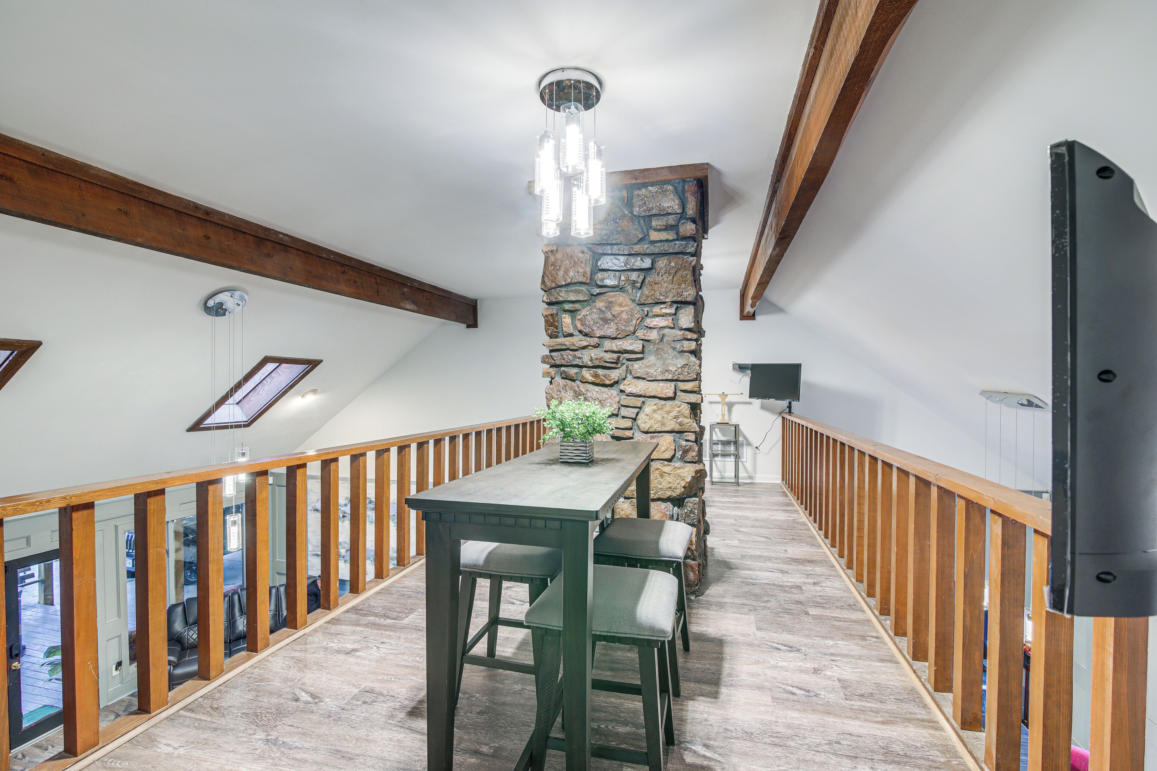 A wooden staircase with a stone wall and a table with chairs.