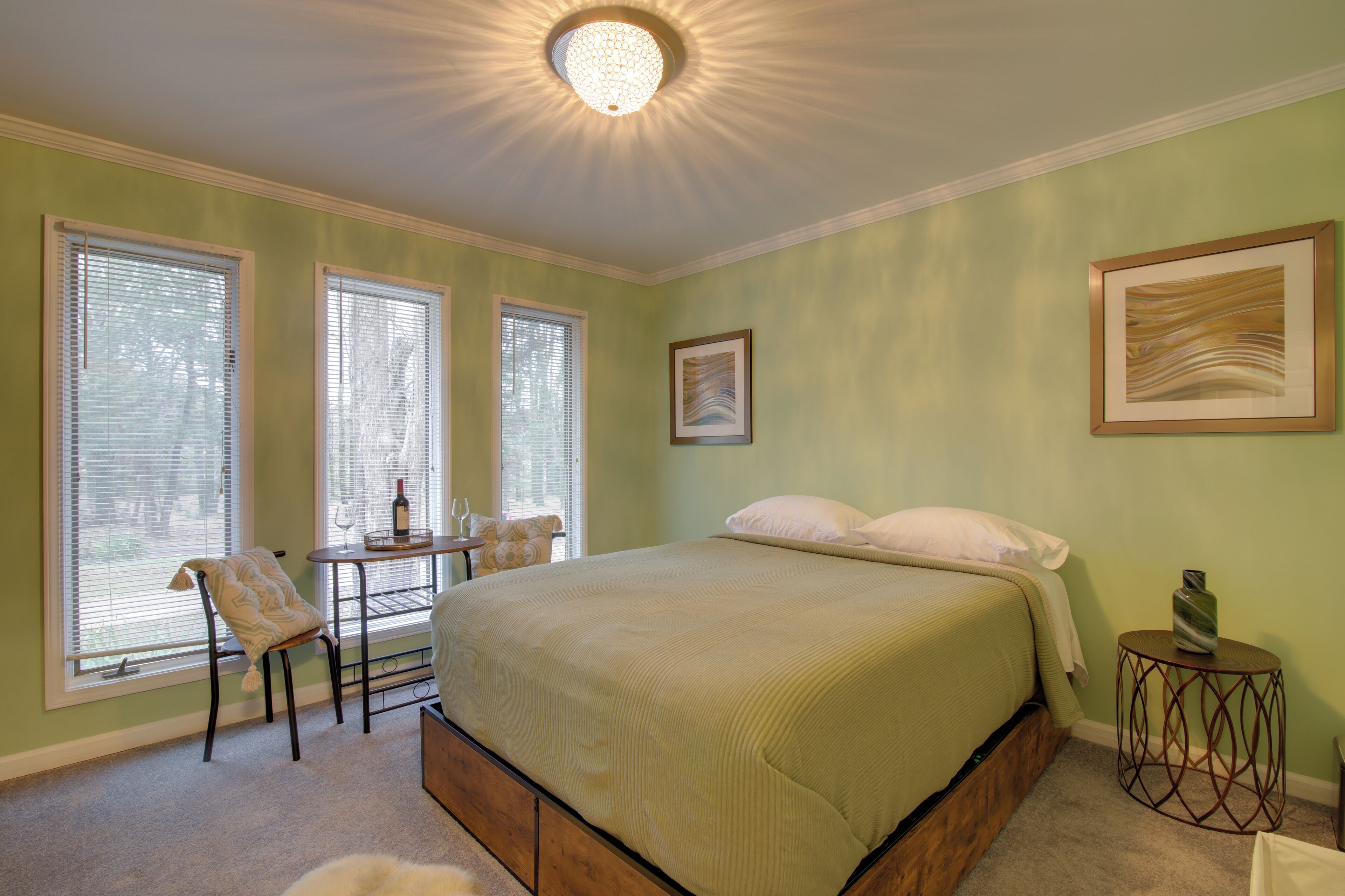 Een slaapkamer met een groot bed, een stoel, een klein tafeltje en een nachtkastje.