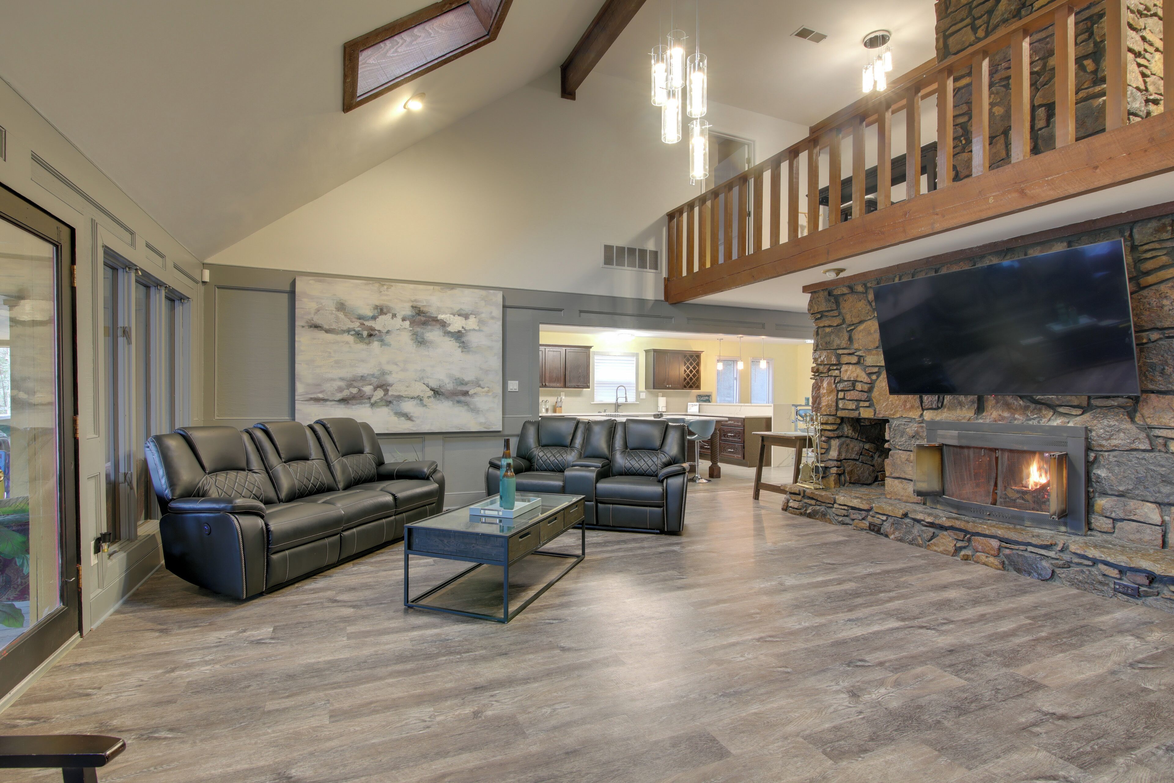 A spacious living room with a stone fireplace, leather sofas, and a large flat-screen TV.