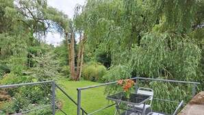 Eine Garten-Terrasse mit Tisch und Stühlen, umgeben von üppigem Grün und Bäumen.