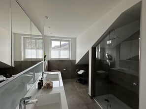 Ein modernes Badezimmer mit einem großen Spiegel, einer Badewanne und einer Duschkabine.