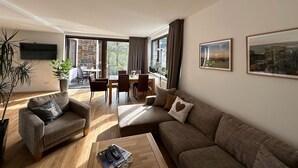 Ein Wohnzimmer mit Sofa, Sessel, Couchtisch und einem Essbereich mit Stühlen und Tisch.