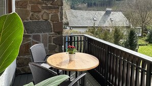 Ein Balkon mit rundem Tisch, Korbstühlen und einem Blumentopf.