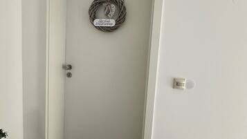 Une porte blanche, avec un paillasson et une enseigne suspendue.