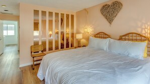 Un dormitorio con una cama grande, un cabecero de madera, una decoración de corazón en la pared y una silla cerca de la ventana.