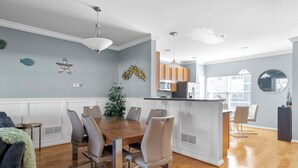 A modern kitchen with wooden cabinets, a central island, and pendant lighting. - Rehoboth Crossing 1 - For 10 (Rehoboth Beach)
