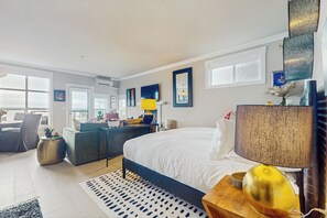 A modern hotel room with a large bed, a desk, a chair, and a view of the outdoors. - Studio Overlooking Saratoga Passage & Cascade Mtns (Langley)