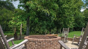 A circular brick fire pit surrounded by wooden chairs in a park setting. - Pool + Riverfront! Couples Retreat in Smoky Mtns (Townsend)