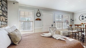 A hotel room with a large bed, a dining area, and a clock on the wall. - Pool + Riverfront! Couples Retreat in Smoky Mtns (Townsend)