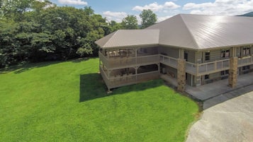 A two-story house with a metal roof, a covered porch, and a well-maintained lawn.