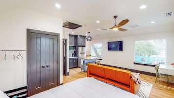 A bedroom with a bed, a desk, a chair, a wardrobe, and a kitchenette.