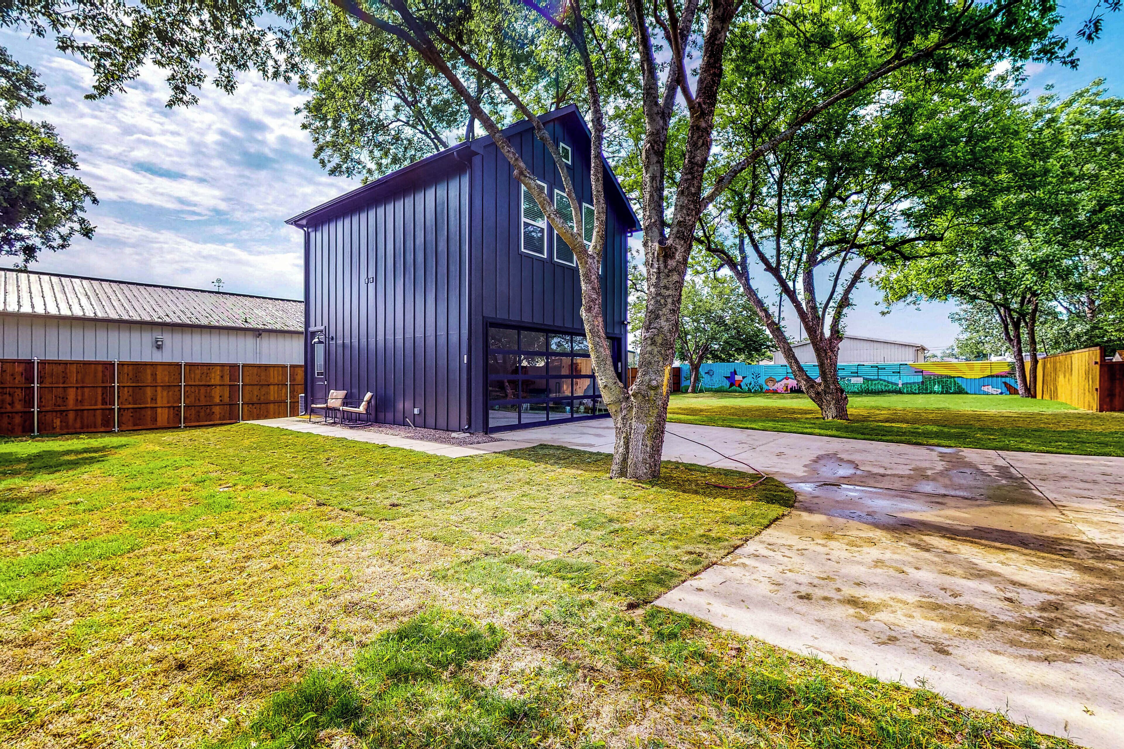 Un bâtiment moderne à l’extérieur sombre, doté de grandes fenêtres et d’une porte de garage bien visible.