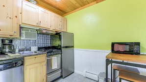 Una cocina con armarios de madera, electrodomésticos de acero inoxidable y una pared verde.