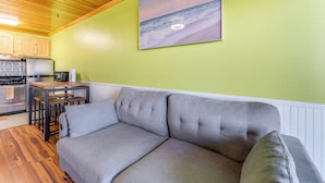 Una cocina moderna con armarios de madera, una mesa de comedor y un sofá gris en una habitación con paredes verdes.
