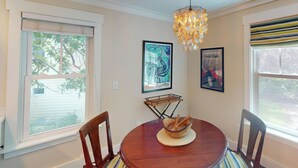 A dining area with a round table, wooden chairs, a chandelier, and artwork on the walls. - Steps to Riverfront: Dtwn Bluffton Studio! (Bluffton)
