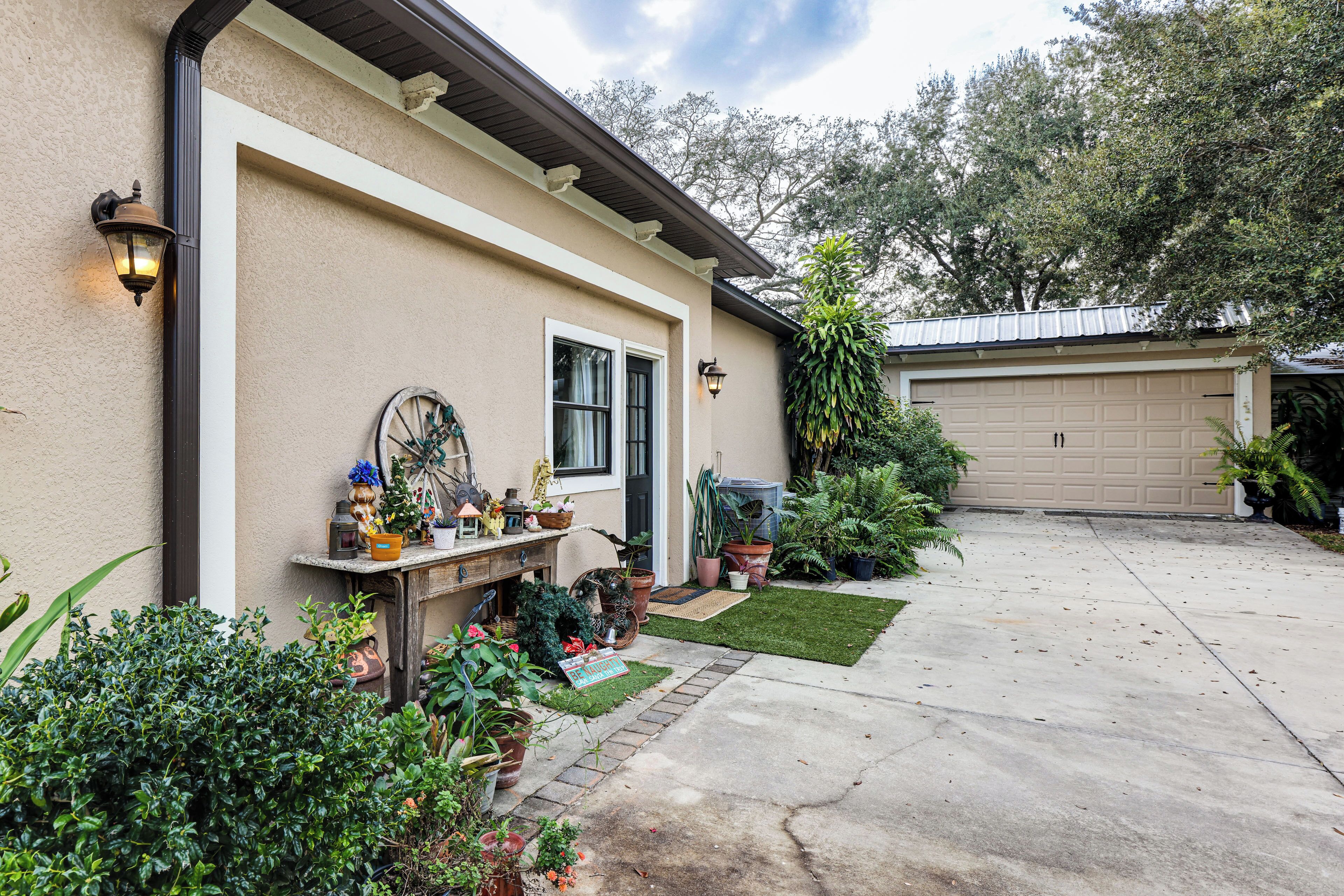 A house with a garage, a front porch with potted plants, and a small lawn.