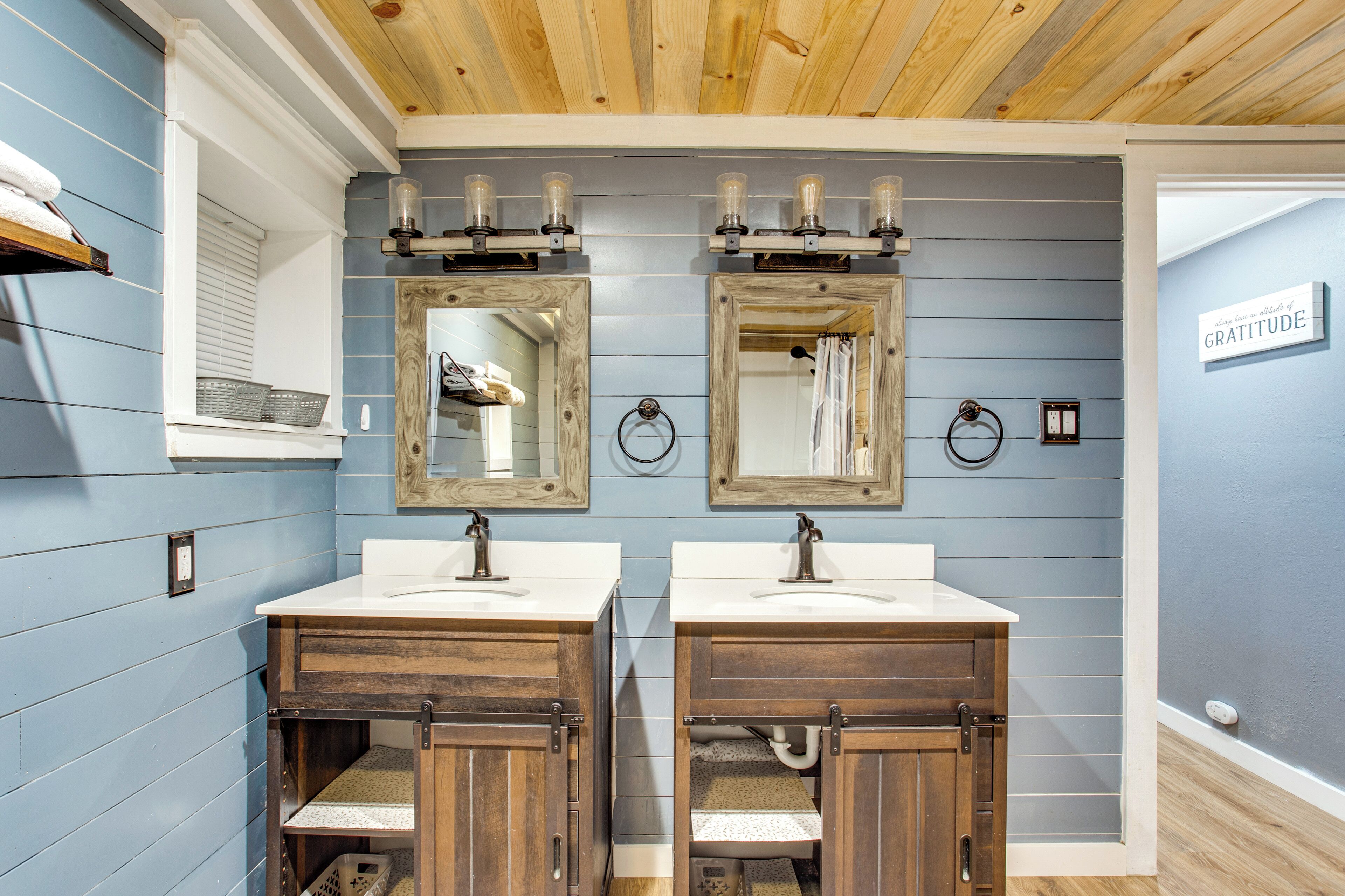 Une salle de bain avec deux lavabos, des meubles en bois et un grand miroir de coiffeuse.