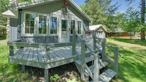 Une cabane dotée d’une véranda, d’une cheminée et d’une fenêtre avec des volets.