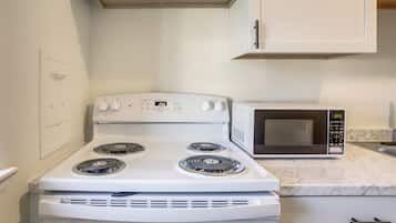 Una cocina con estufa blanca, microondas y encimera de mármol.