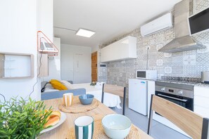 A modern kitchen with a microwave, oven, and a small dining area with a table and chairs. - WELCS STUDIO 307 EMP with sea views (Empuriabrava)