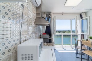 A kitchen with patterned tiles, a microwave, a stove, and a view of a lake through open doors. - WELCS STUDIO 307 EMP with sea views (Empuriabrava)
