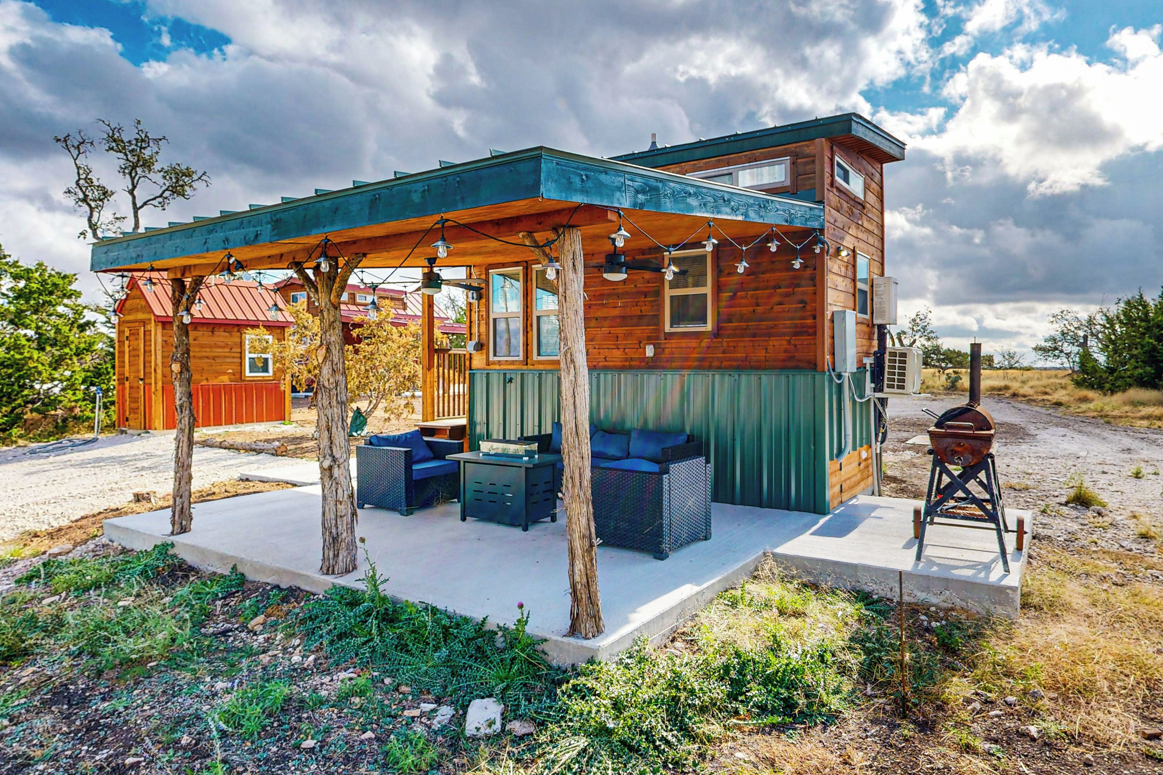 Eine Holzhütte mit überdachter Veranda, Sitzgelegenheiten im Freien und einem Grill.
