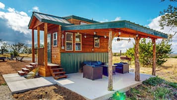 A wooden cabin with a covered porch, outdoor seating, and a view of the surrounding landscape.