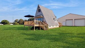 Une maison avec un toit à forte pente, une terrasse en bois et un garage.