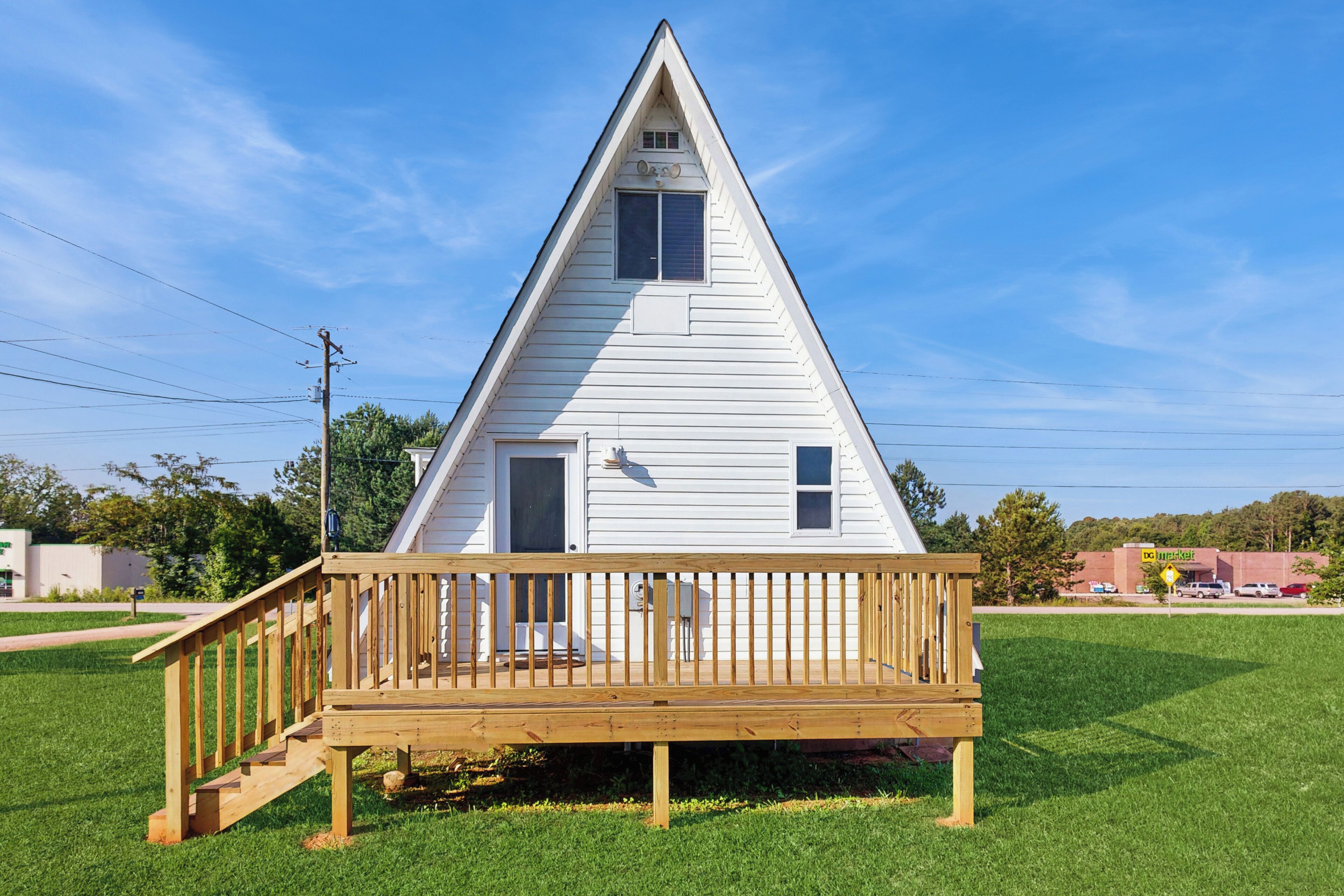 A white, triangular-shaped house with a wooden deck and a small porch.