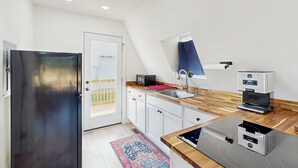 Une cuisine moderne dotée d’un réfrigérateur en acier inoxydable, d’un plan de travail en bois et d’une machine à café intégrée.