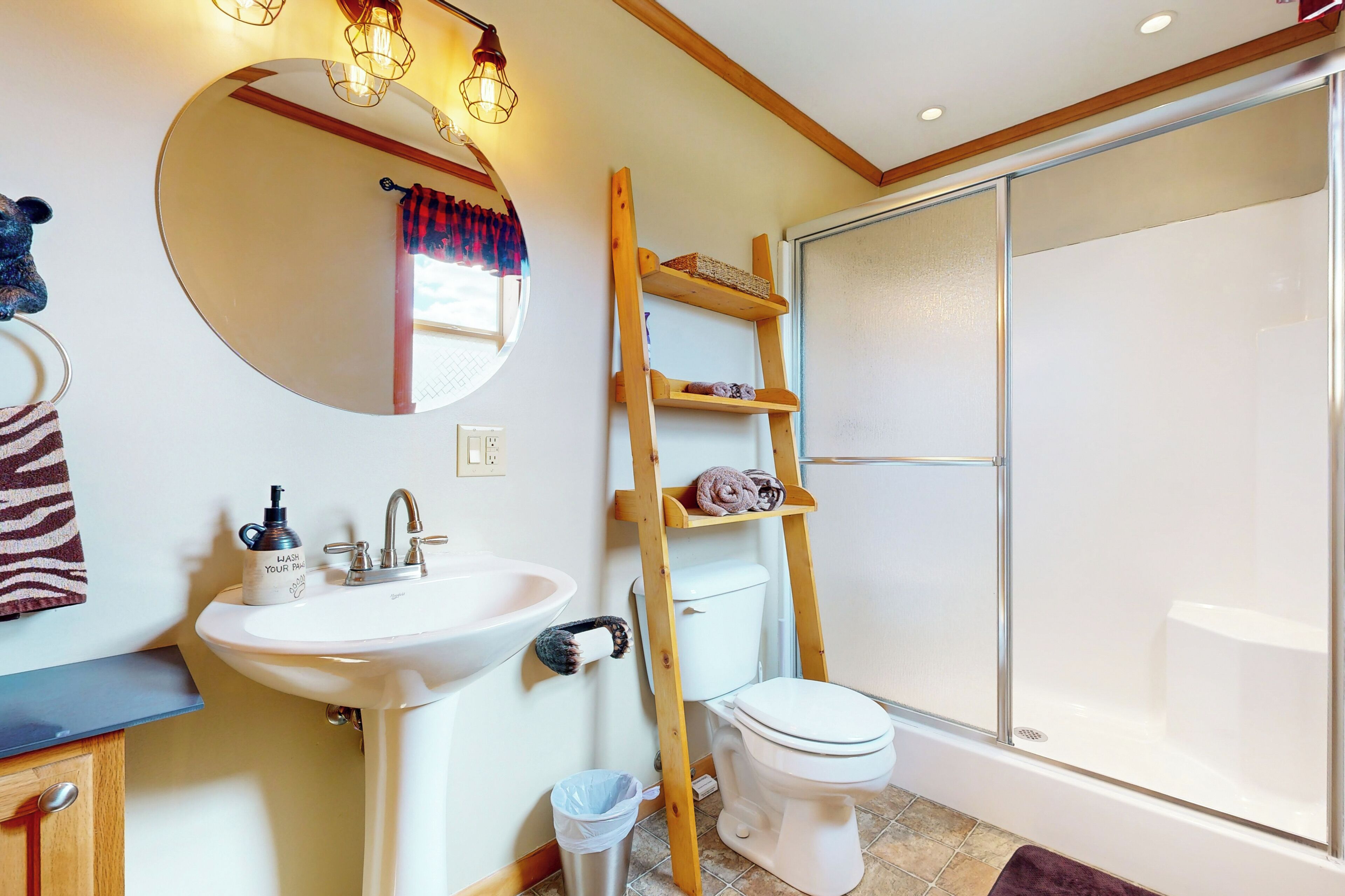 A bathroom with a sink, mirror, toilet, and a wooden ladder shelf.