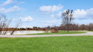 A park with a pond, picnic tables, and wooden structures.