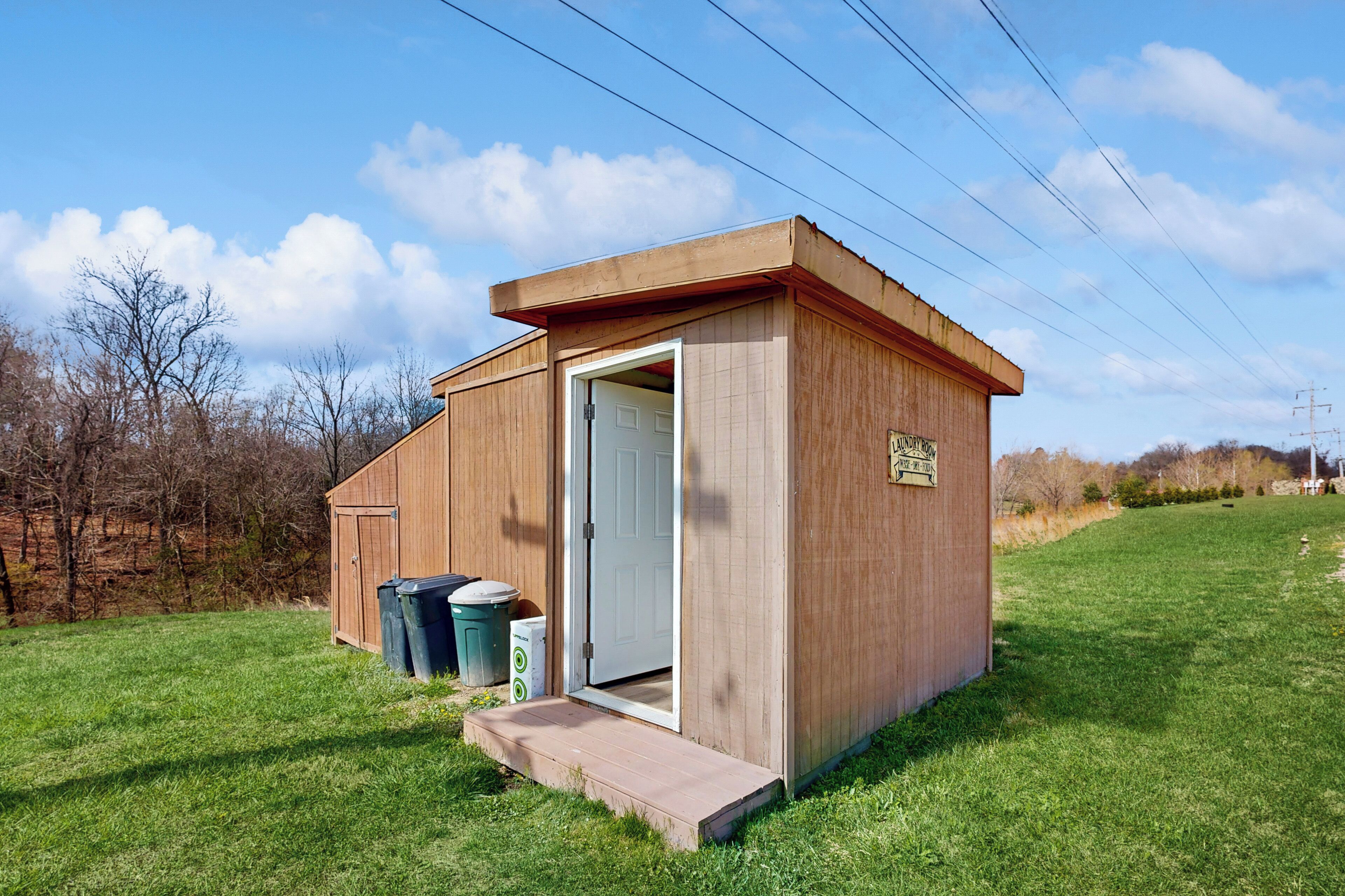 Una pequeña estructura de madera con una puerta, una rampa que lleva a la entrada y un cartel lateral.