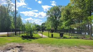Ein von Zäunen umgebenes Parkareal mit einem Feldweg, der zu einer Wiese führt.
