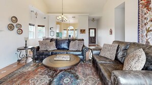 A spacious living room with a leather sofa, a coffee table, and a patterned rug. - 3BR Updated Mtn-view Home w/ Hot Tub & Fireplace (Copperopolis)