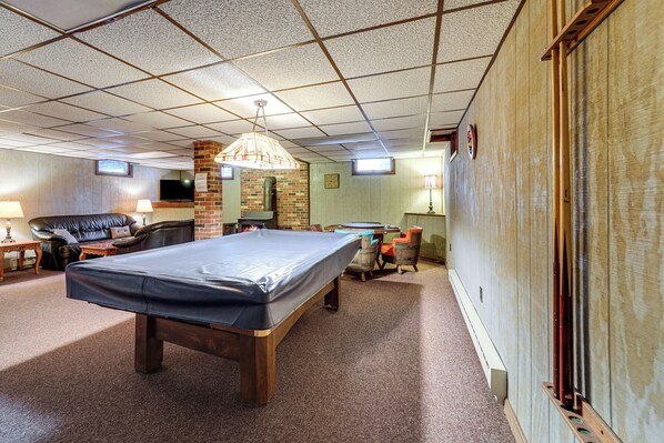 A spacious room with a pool table, a leather sofa, and a brick fireplace. - Roaring Spring Horse Farm Getaway w/ Game Room (Roaring Spring)