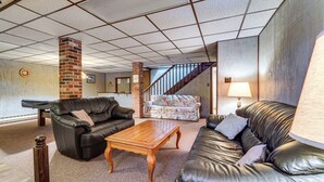 A spacious living room with leather sofas, a wooden coffee table, and a staircase leading to an upper level. - Roaring Spring Horse Farm Getaway w/ Game Room (Roaring Spring)