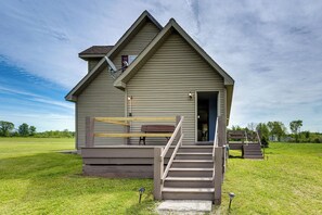 A single-story building with a front porch, a staircase leading to the entrance, and a small outdoor seating area. - Backcountry Living Home Near Hiking in Sprakers! (Sprakers)