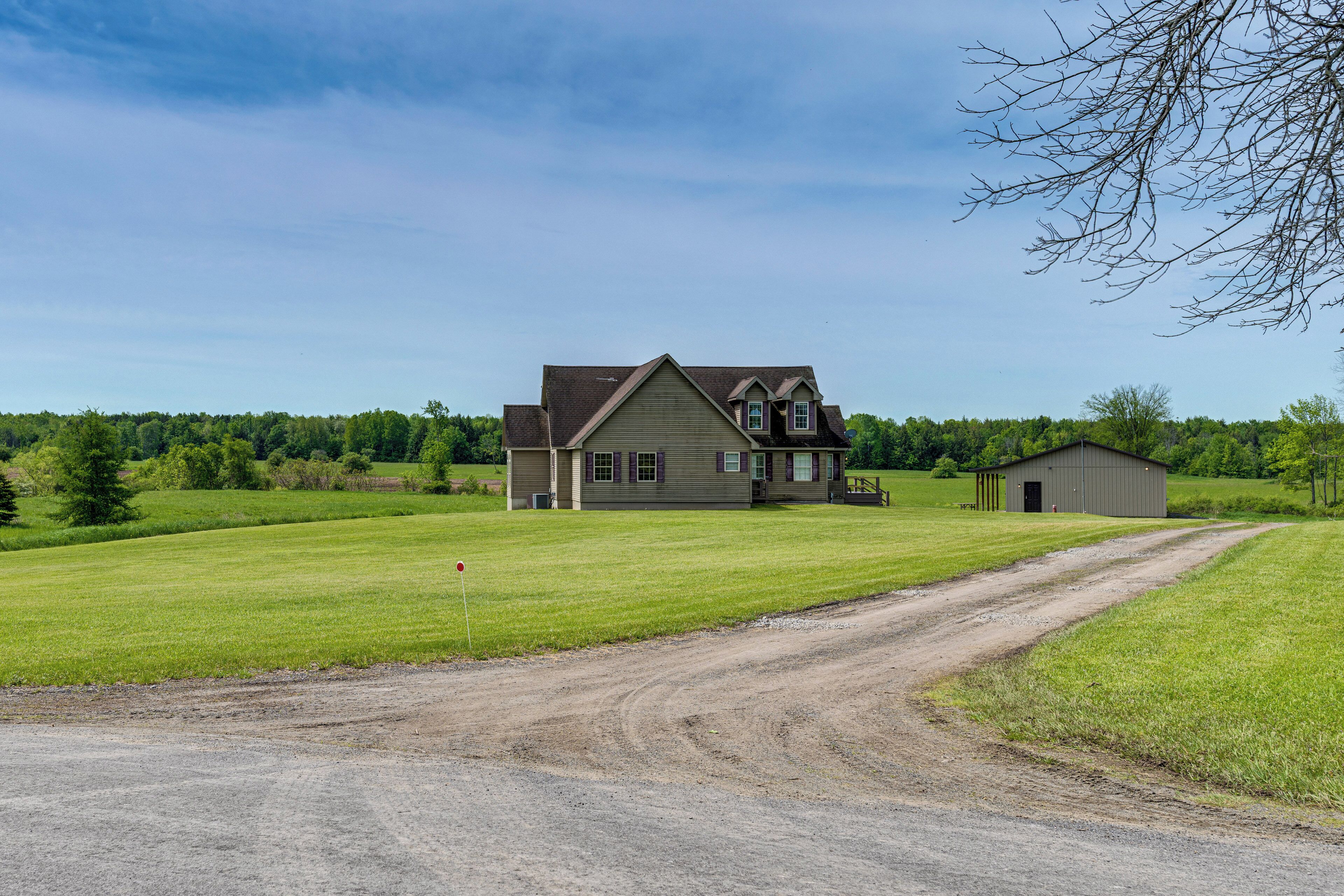 A two-story house with a large front lawn and a gravel driveway.