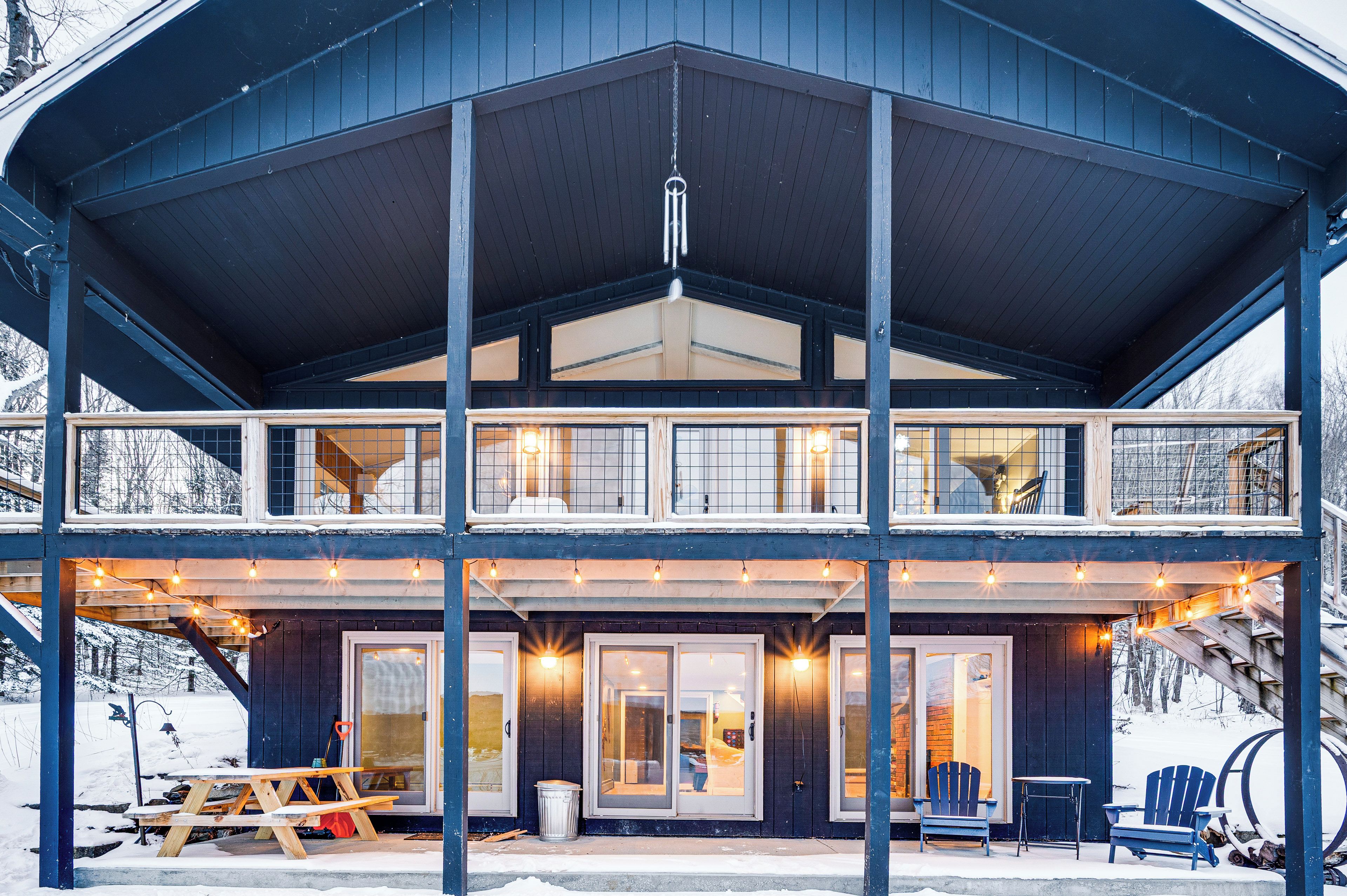 A two-story lodge with a covered porch, large windows, and a wooden deck.