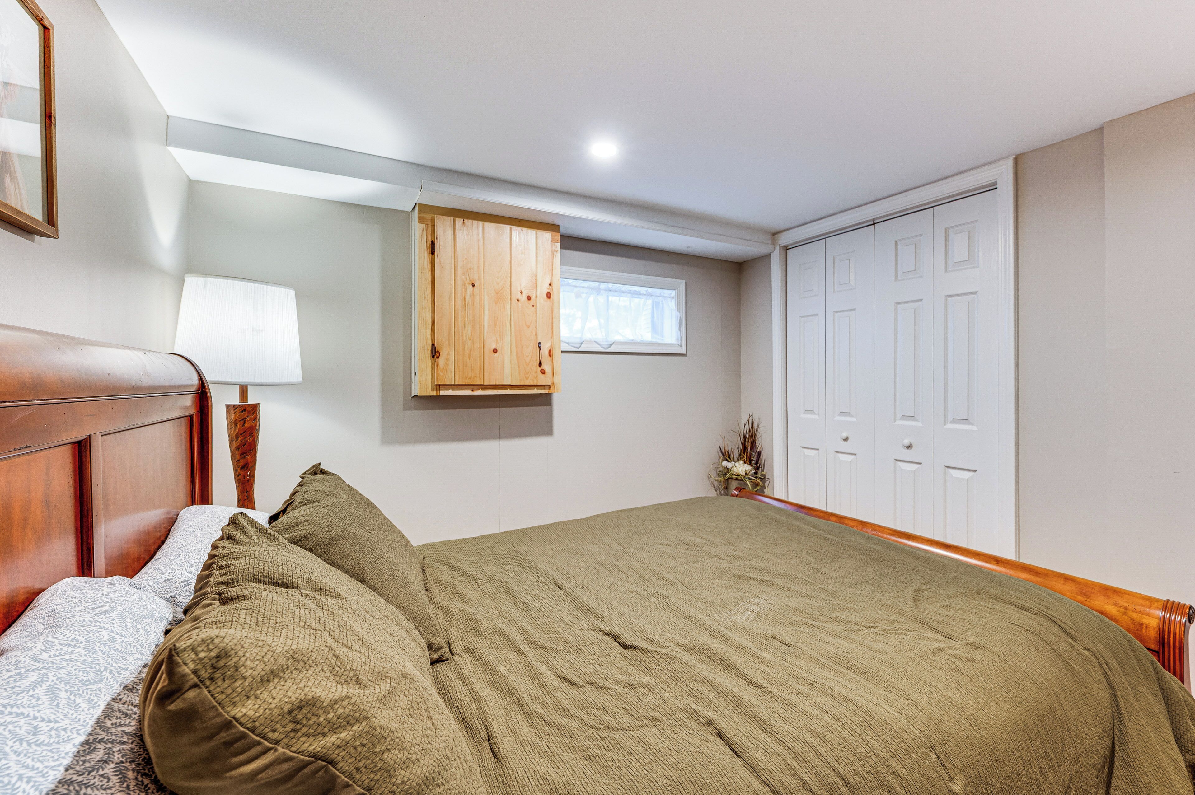 A bedroom with a wooden bed, a window, a wooden cabinet, and a wardrobe.