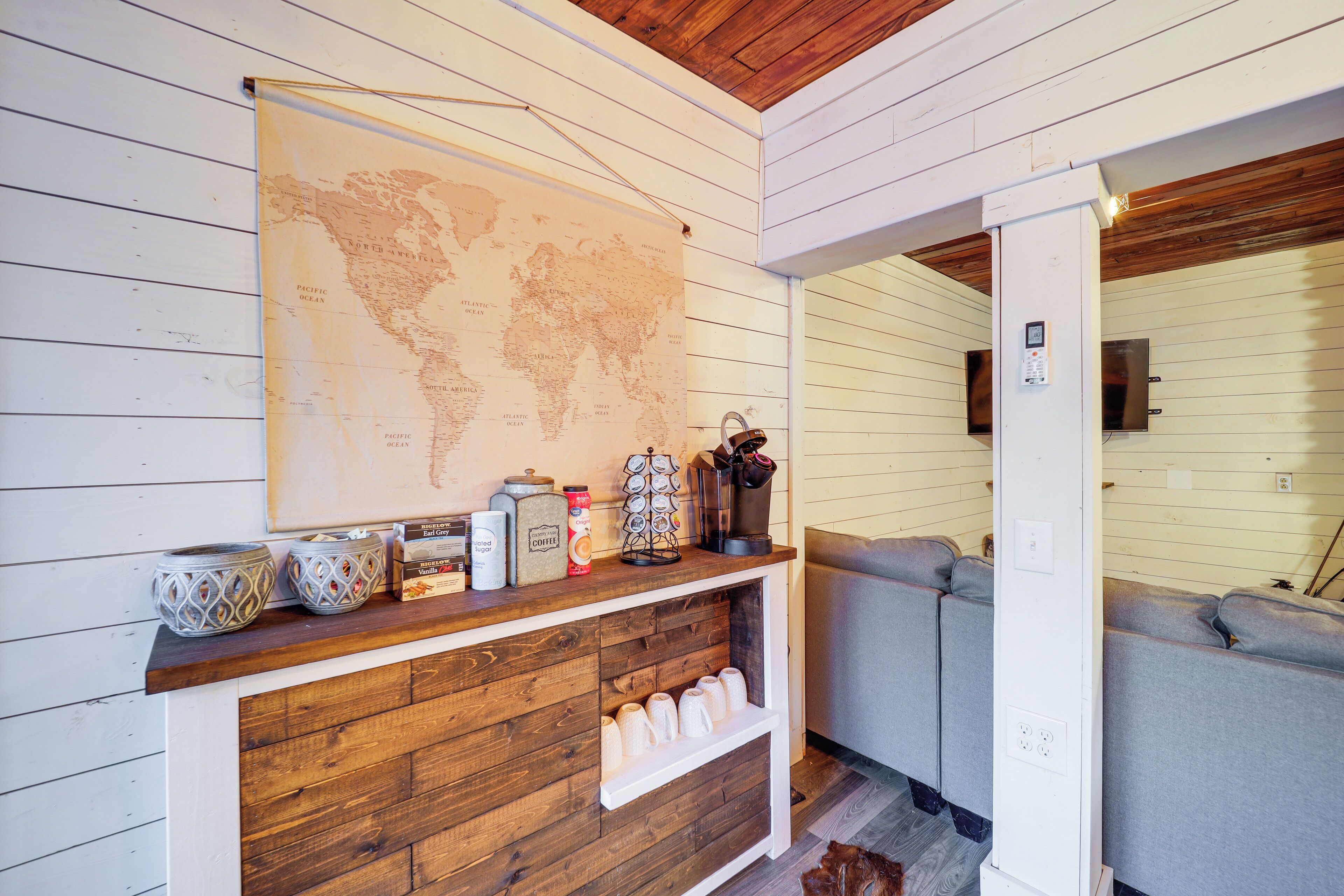 A cozy room with a wooden wall, a world map, and a coffee station with various items.