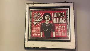 Um cartaz emoldurado com texto e uma figura central, fixado na parede.