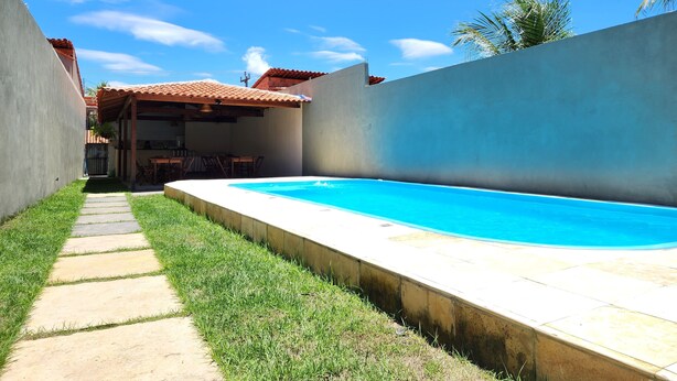 A backyard with a swimming pool, a patio area, and a covered seating space. - Pousada Nossa Casa Barreirinhas (Barreirinhas)