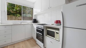 Eine moderne Küche mit weißen Schränken, einem Gasherd, einer Mikrowelle und einem roten Toaster.