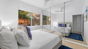 Ein modernes Schlafzimmer mit einem großen Bett, einem kleineren Bett und einer Glaskabine.