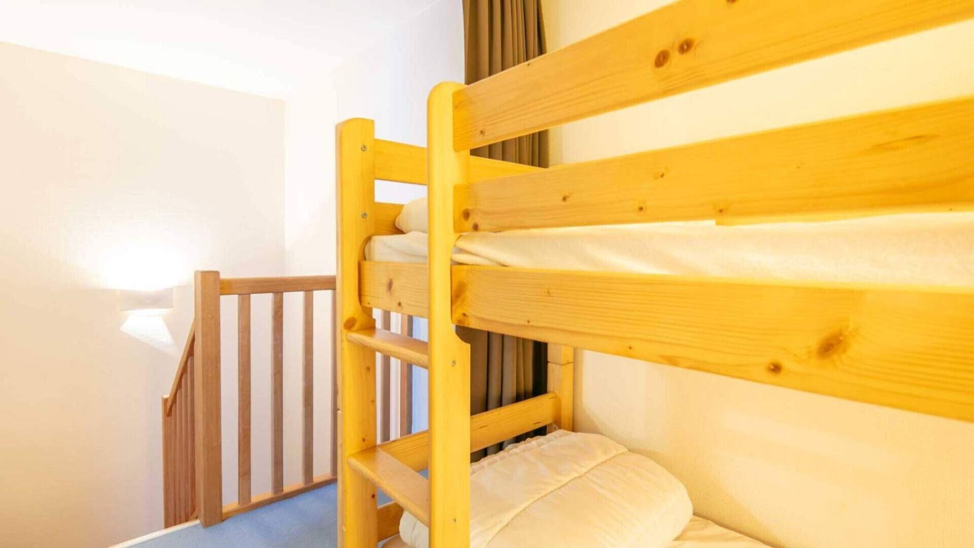 A bunk bed with a wooden frame and a mattress.