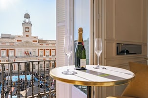 Un balcone con vista su un edificio storico, una bottiglia di champagne e due bicchieri su un tavolo.